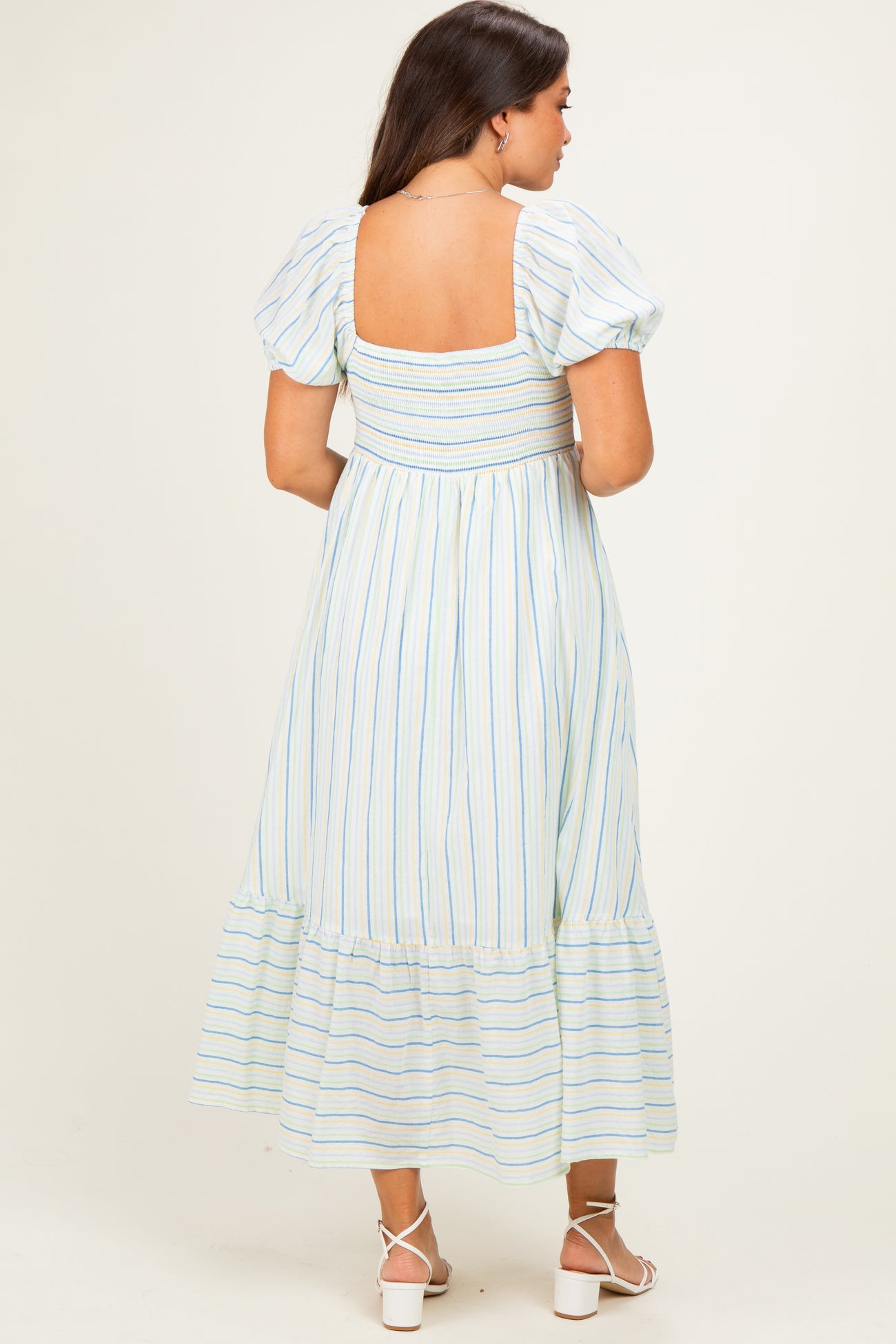 woman wearing a striped maternity maxi dress with puff sleeves and a smocked back, featuring a tiered hem