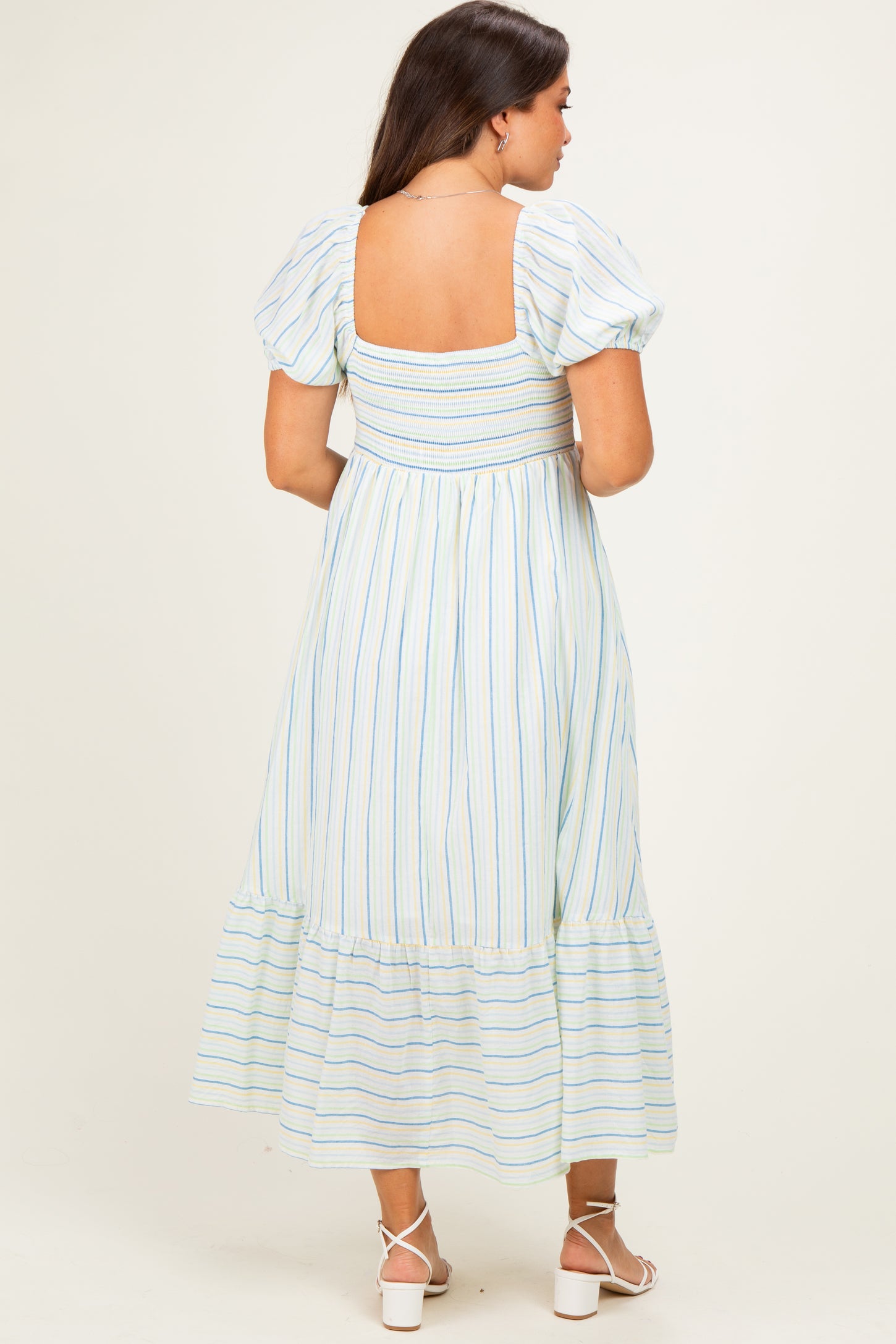 woman wearing a striped maternity maxi dress with puff sleeves and a smocked back, featuring a tiered hem