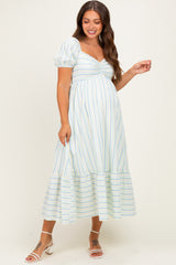woman wearing a light blue and white striped maternity dress with puff sleeves and a tiered hem, showing her baby bump