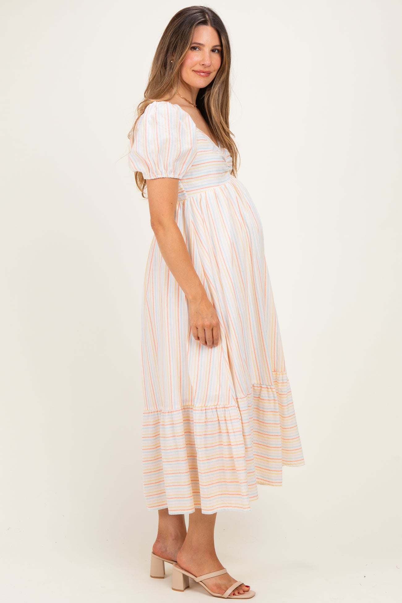 woman wearing a striped maternity dress with short puff sleeves and a tiered skirt, showing her baby bump