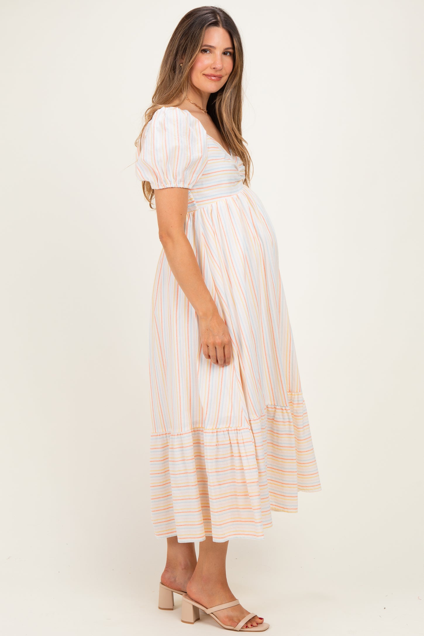 woman wearing a striped maternity dress with short puff sleeves and a tiered skirt, showing her baby bump