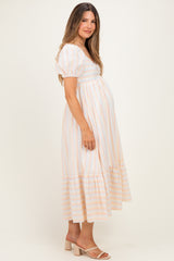 woman wearing a striped maternity dress with short puff sleeves and a tiered skirt, showing her baby bump