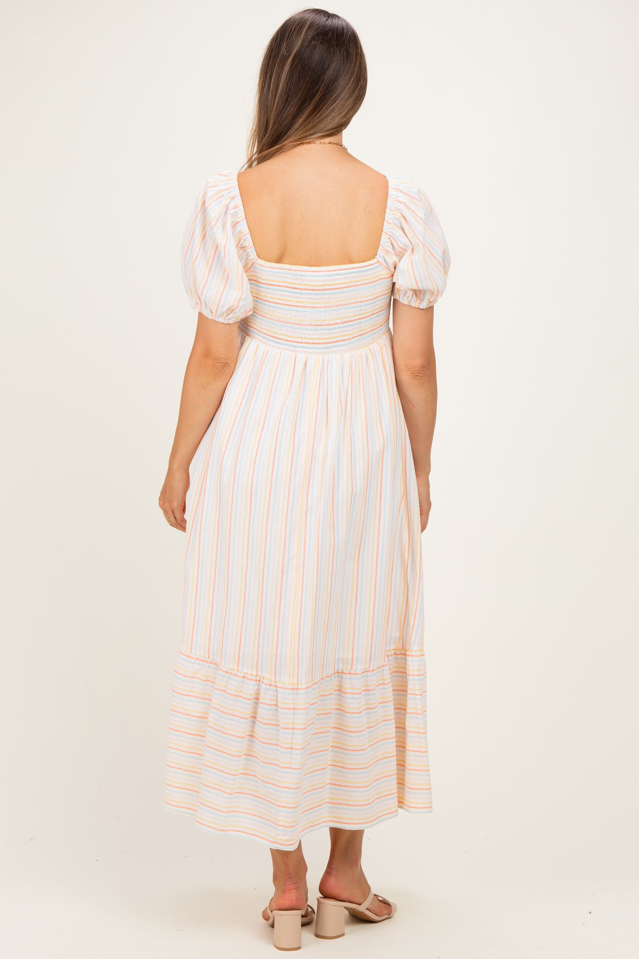 woman wearing a striped maternity maxi dress with puff sleeves and a smocked bodice, showing her back