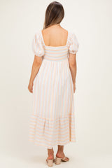 woman wearing a striped maternity maxi dress with puff sleeves and a smocked bodice, showing her back