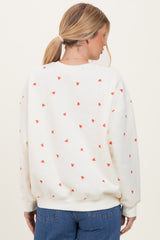woman wearing a cream oversized sweatshirt with red heart print, viewed from the back