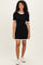 woman wearing a black ribbed short sleeve dress with white ruffle trim and white sneakers