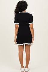 woman wearing a black ribbed short sleeve dress with white ruffled trim, shown from the back