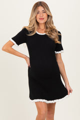 woman wearing a black ribbed maternity dress with white ruffled sleeves and hem, showcasing her baby bump
