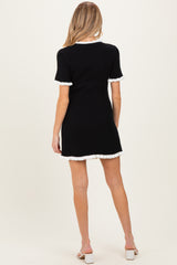 woman wearing a black ribbed maternity dress with white trimmed sleeves, showing the back view