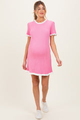 woman wearing a pink ribbed maternity dress with white ruffle details and a visible baby bump