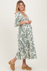 woman wearing a white maternity dress with green paisley print and a visible baby bump