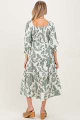 woman wearing a white maternity dress with green paisley print and puff sleeves, showing the back view