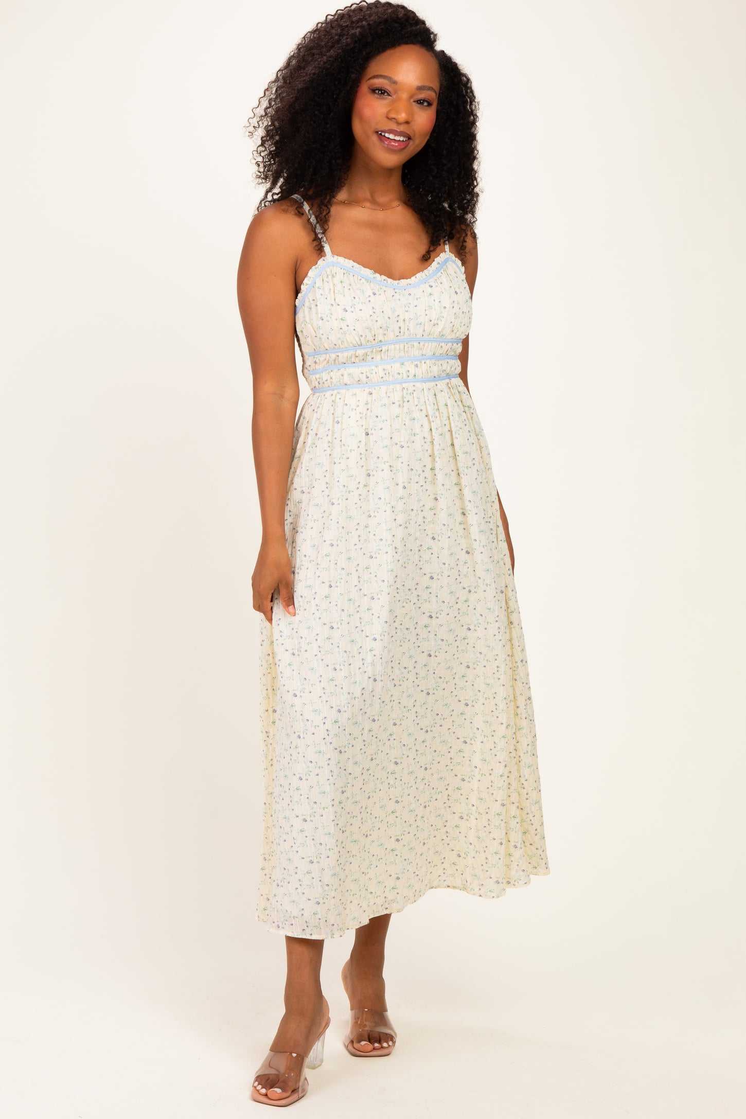 woman wearing a floral midi dress with thin straps and an elasticized waist, styled with a light color palette