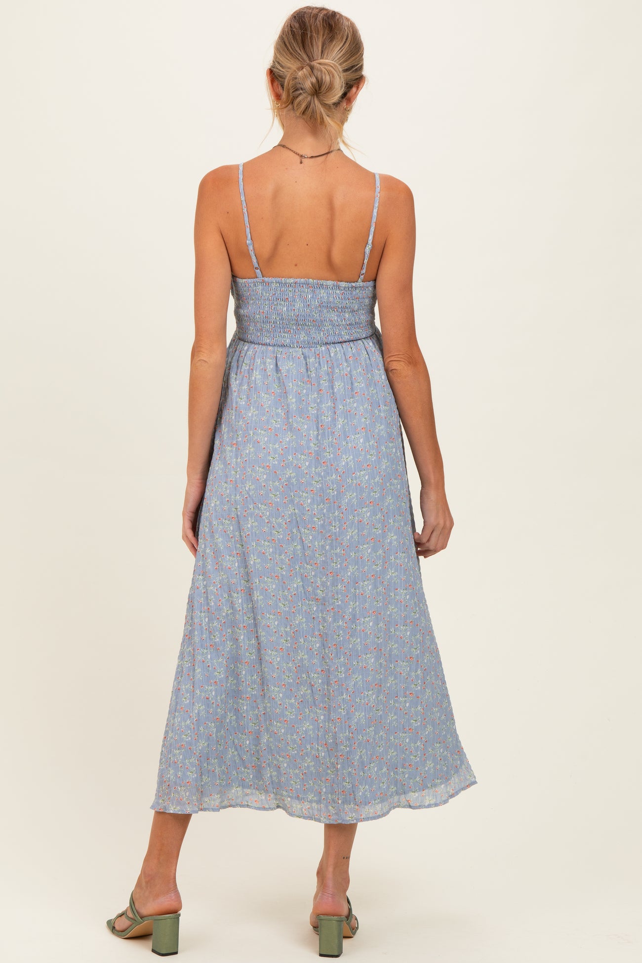 woman wearing a blue floral maternity maxi dress with adjustable straps and a smocked bodice, showing her back