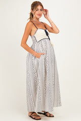 woman wearing a striped maternity maxi dress with adjustable straps and pockets, showing her baby bump