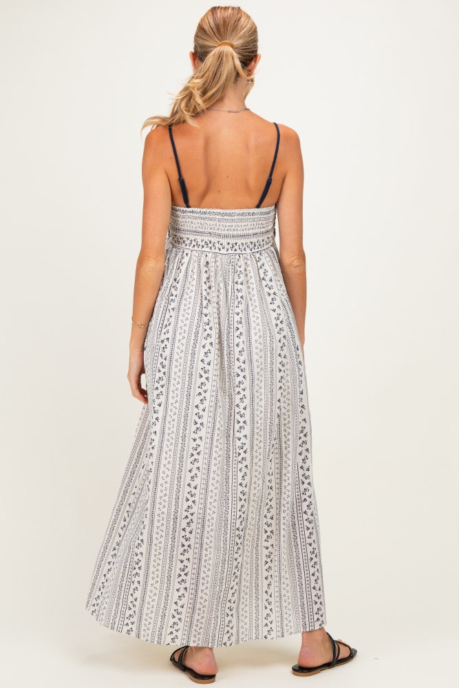 woman wearing a white and navy striped maternity maxi dress with a smocked bodice and adjustable spaghetti straps
