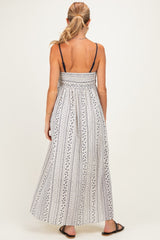 woman wearing a white and navy striped maternity maxi dress with a smocked bodice and adjustable spaghetti straps