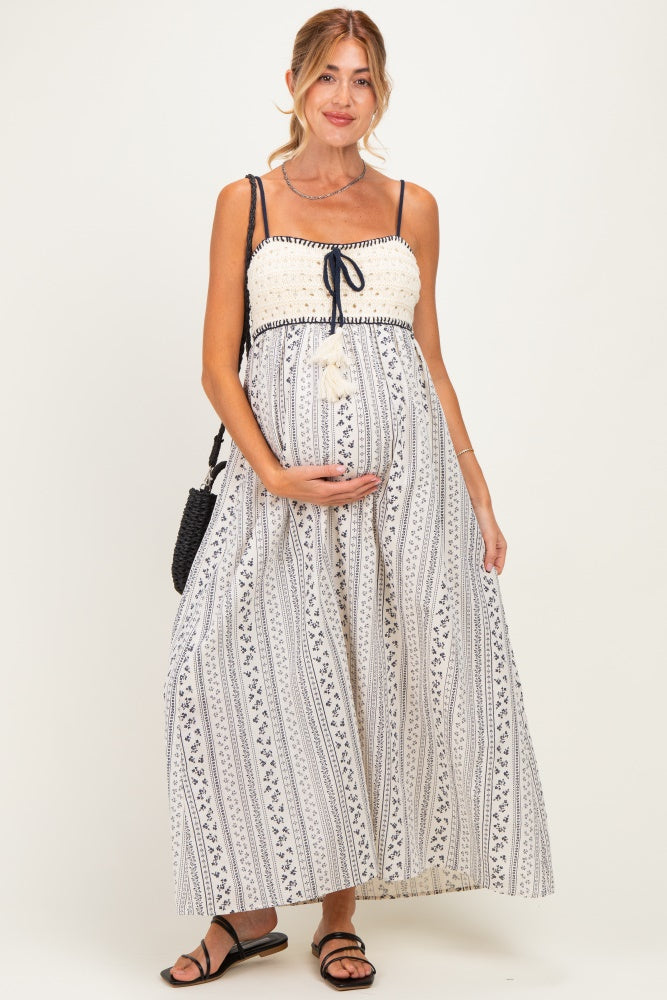 woman wearing a white patterned maternity maxi dress with a tie strap and holding her baby bump