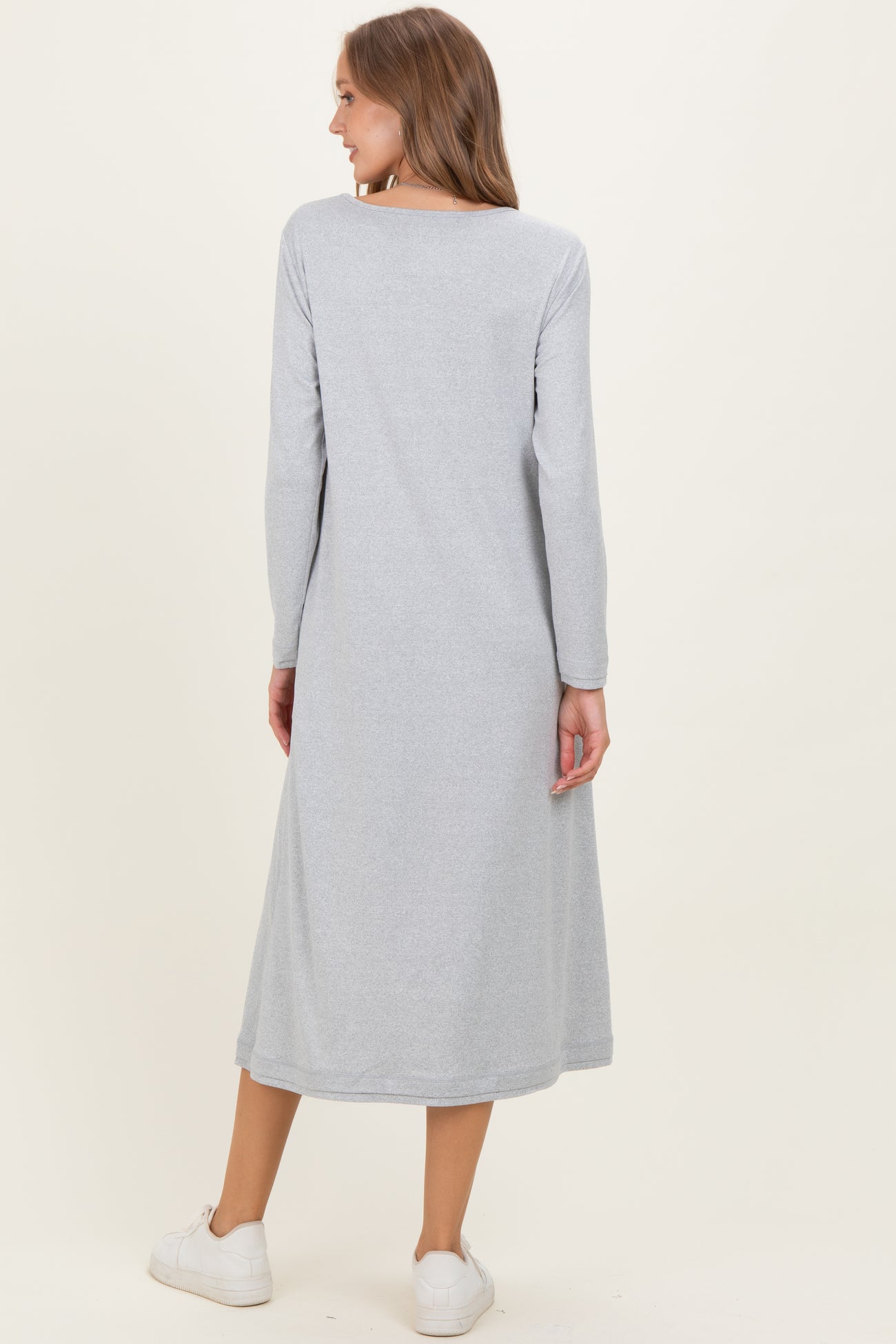 woman wearing a light gray long sleeve maternity dress, shown from the back, with a relaxed fit and ankle length