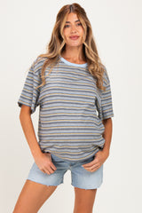 woman wearing a striped maternity top in blue and mustard with blue shorts and a visible baby bump