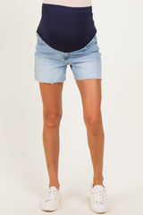 woman wearing a navy maternity belly band with light blue denim maternity shorts and white sneakers