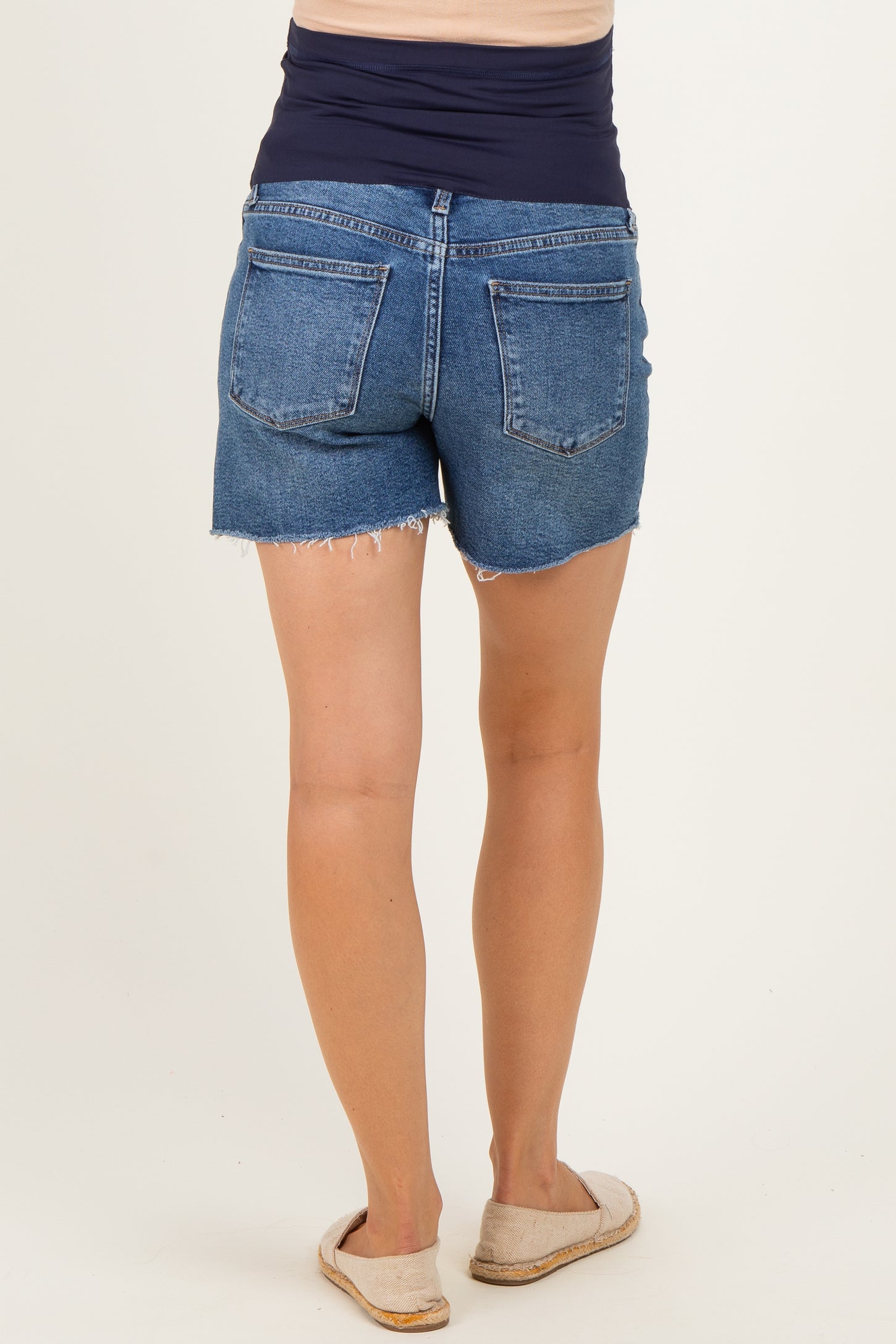 woman wearing maternity denim shorts with a frayed hem, showing a casual and comfortable fit from the back