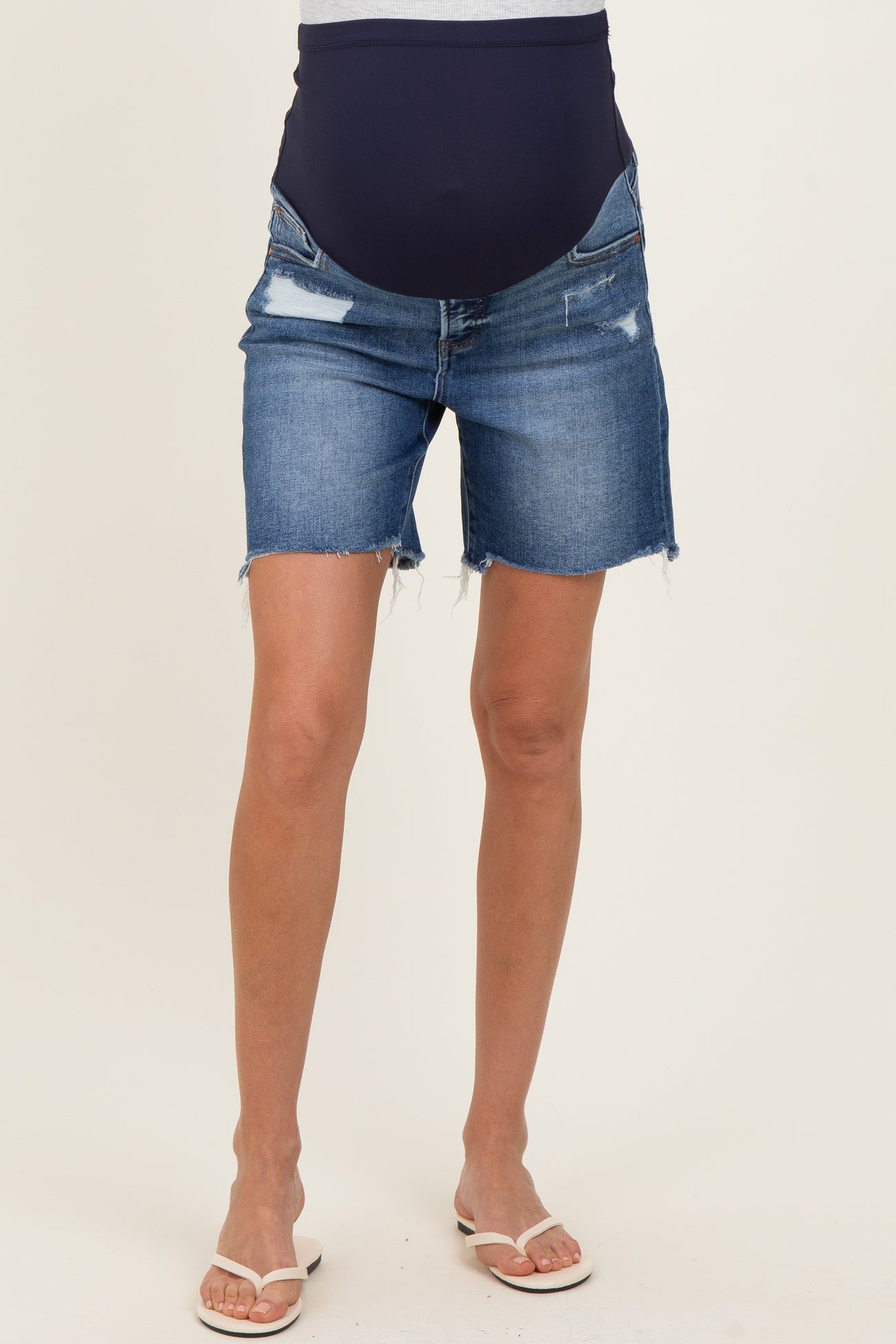 woman wearing dark blue distressed maternity shorts with a supportive belly band