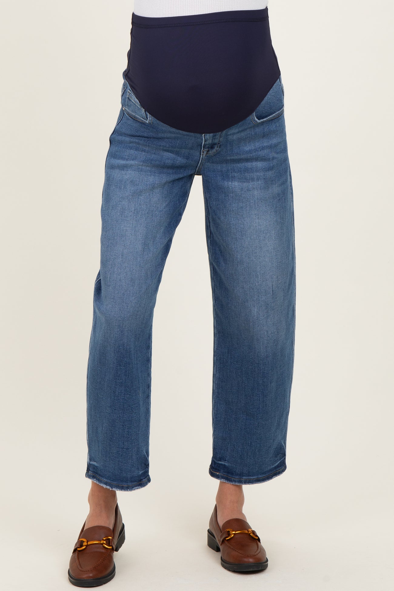 woman wearing blue maternity jeans with a dark waistband and cropped legs, standing in a neutral pose