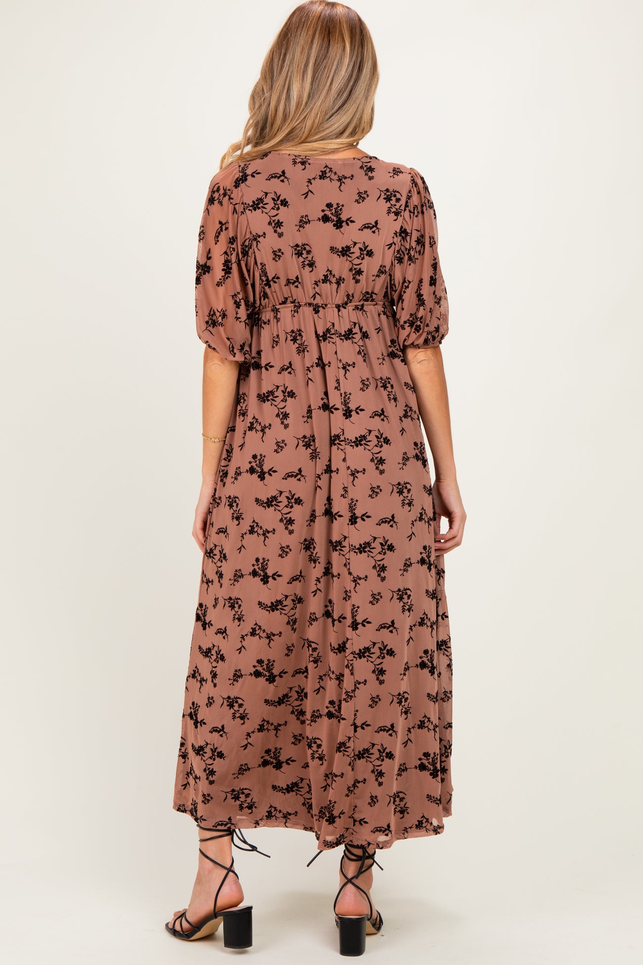 woman wearing a brown floral print maternity maxi dress with puff sleeves, view from the back