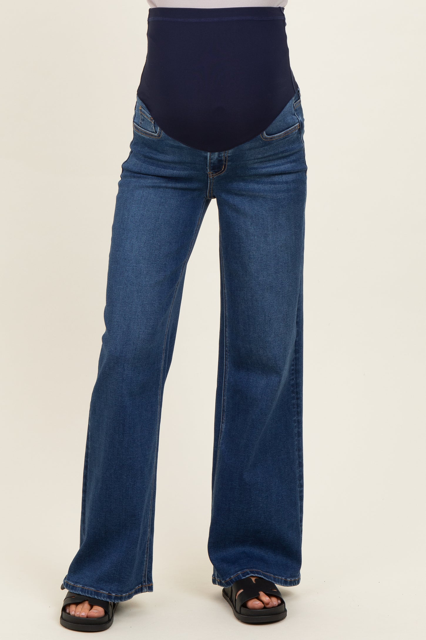 maternity wear in dark blue flared jeans with a supportive belly panel, worn by a model from the waist down