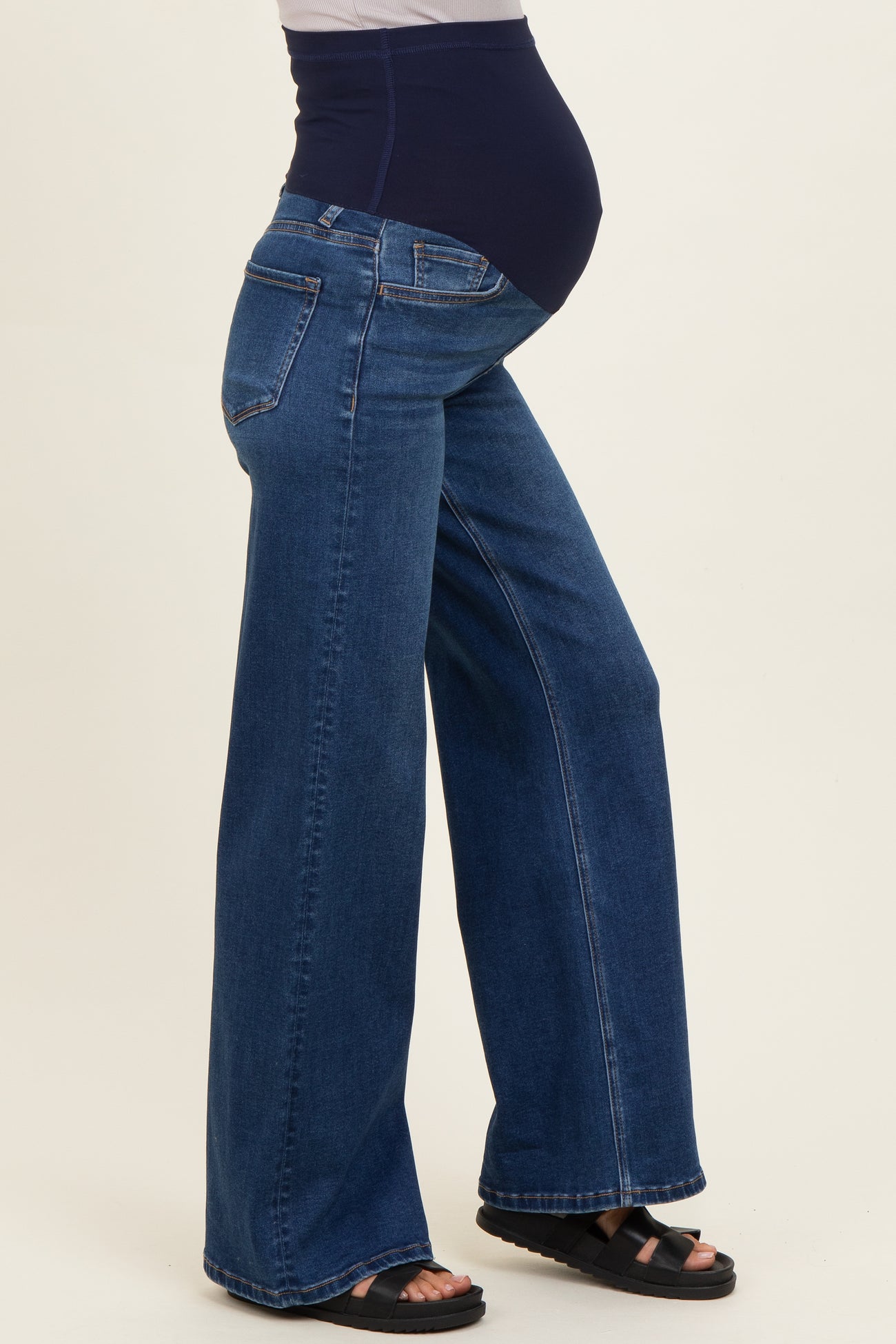 woman wearing dark blue maternity wide-leg jeans with a high waistband and visible baby bump
