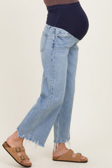 woman wearing light wash maternity jeans with frayed hem and a navy maternity top, showing her baby bump