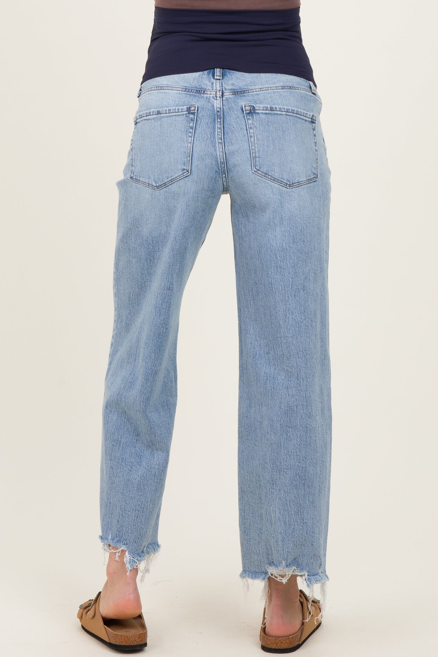 woman wearing light blue maternity jeans with a relaxed fit and raw hem, shown from the back