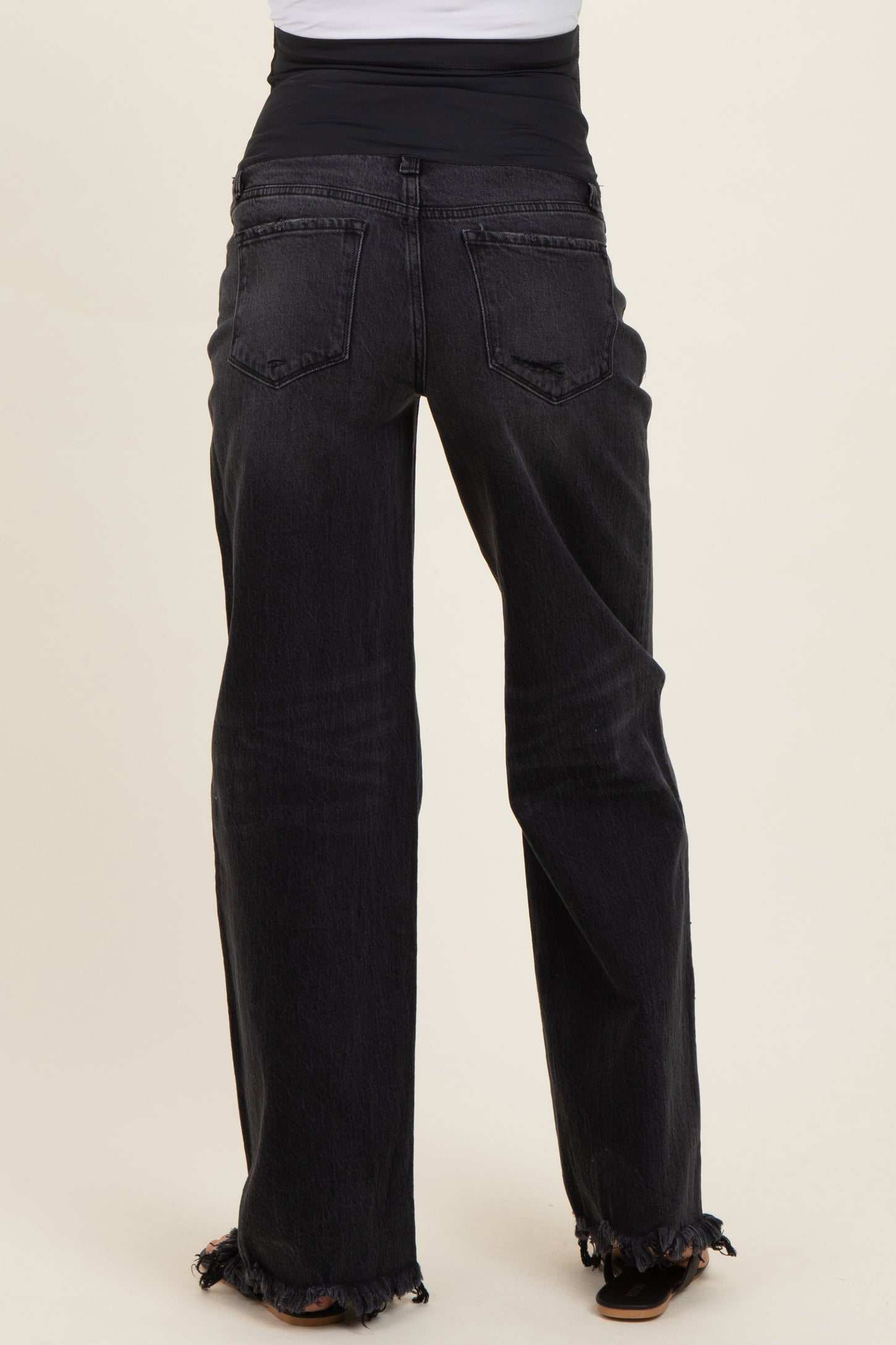 woman wearing black maternity jeans with a frayed hem and a stretchy waistband, viewed from the back