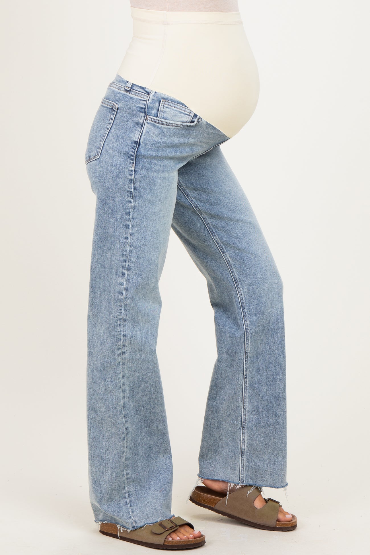 woman wearing light blue maternity jeans with a stretchy belly panel and frayed hem, showing her baby bump