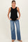 woman wearing a black ribbed maternity tank top and light wash wide-leg jeans, posing with hands in pockets