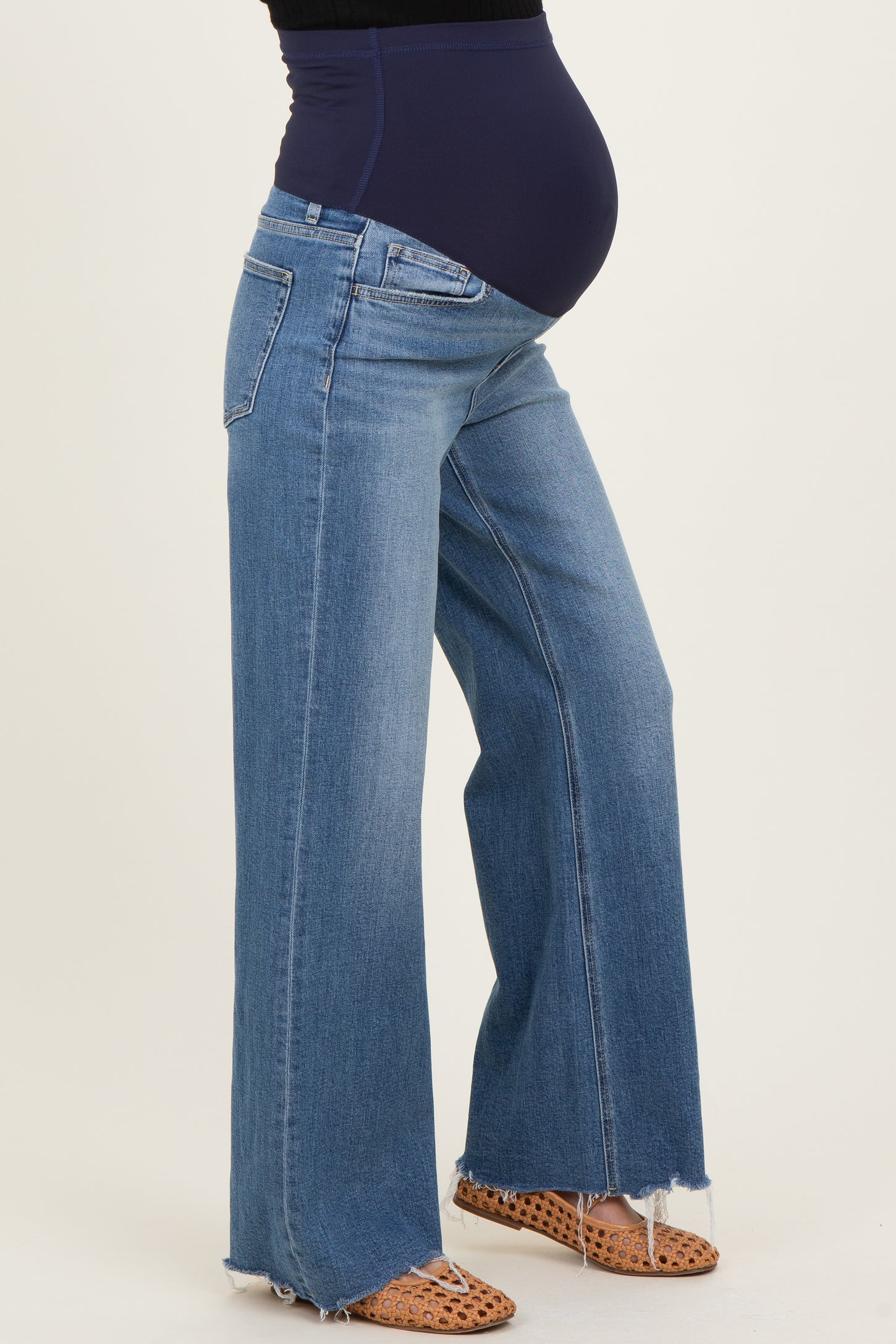 woman wearing light blue maternity wide-leg jeans with a navy blue belly panel and a visible baby bump