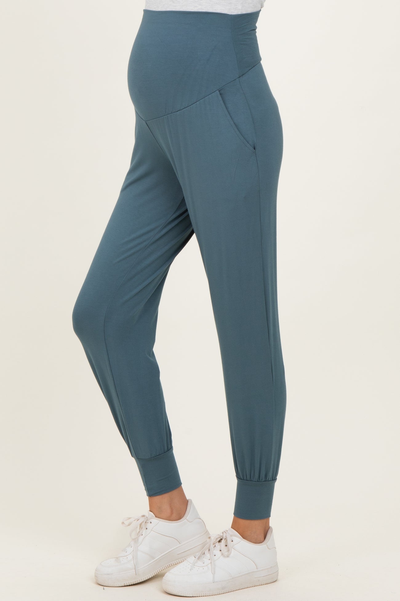 woman wearing dark teal maternity joggers with a high waistband and elastic cuffs