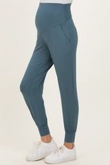 woman wearing dark teal maternity joggers with a high waistband and elastic cuffs
