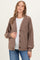 woman wearing a brown textured maternity cardigan over a white top and holding her baby bump