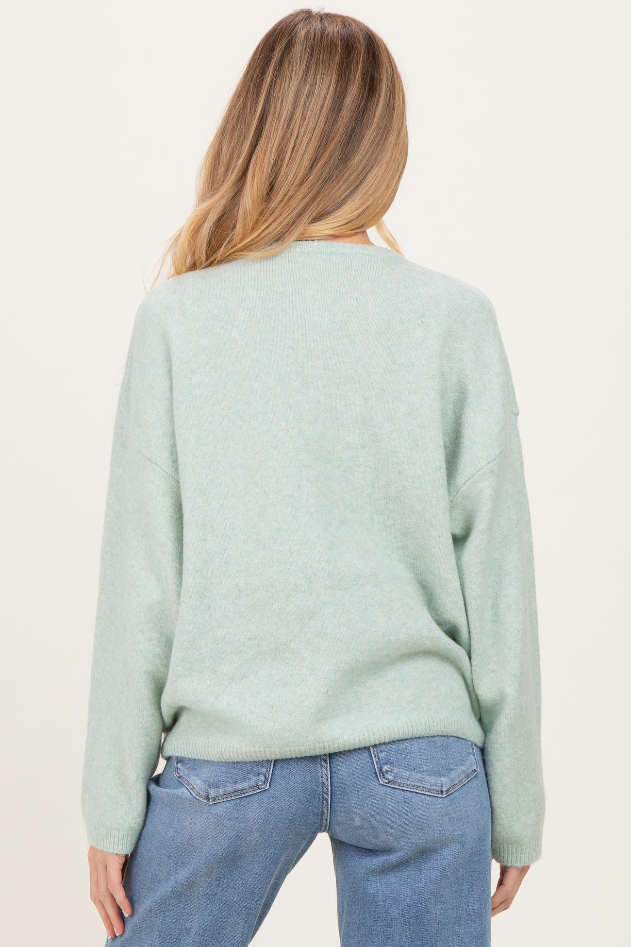 woman wearing a mint green maternity sweater with a relaxed fit and long sleeves, showing the back view