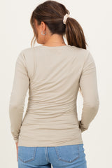 woman wearing a beige long sleeve maternity top, viewed from the back, paired with blue jeans