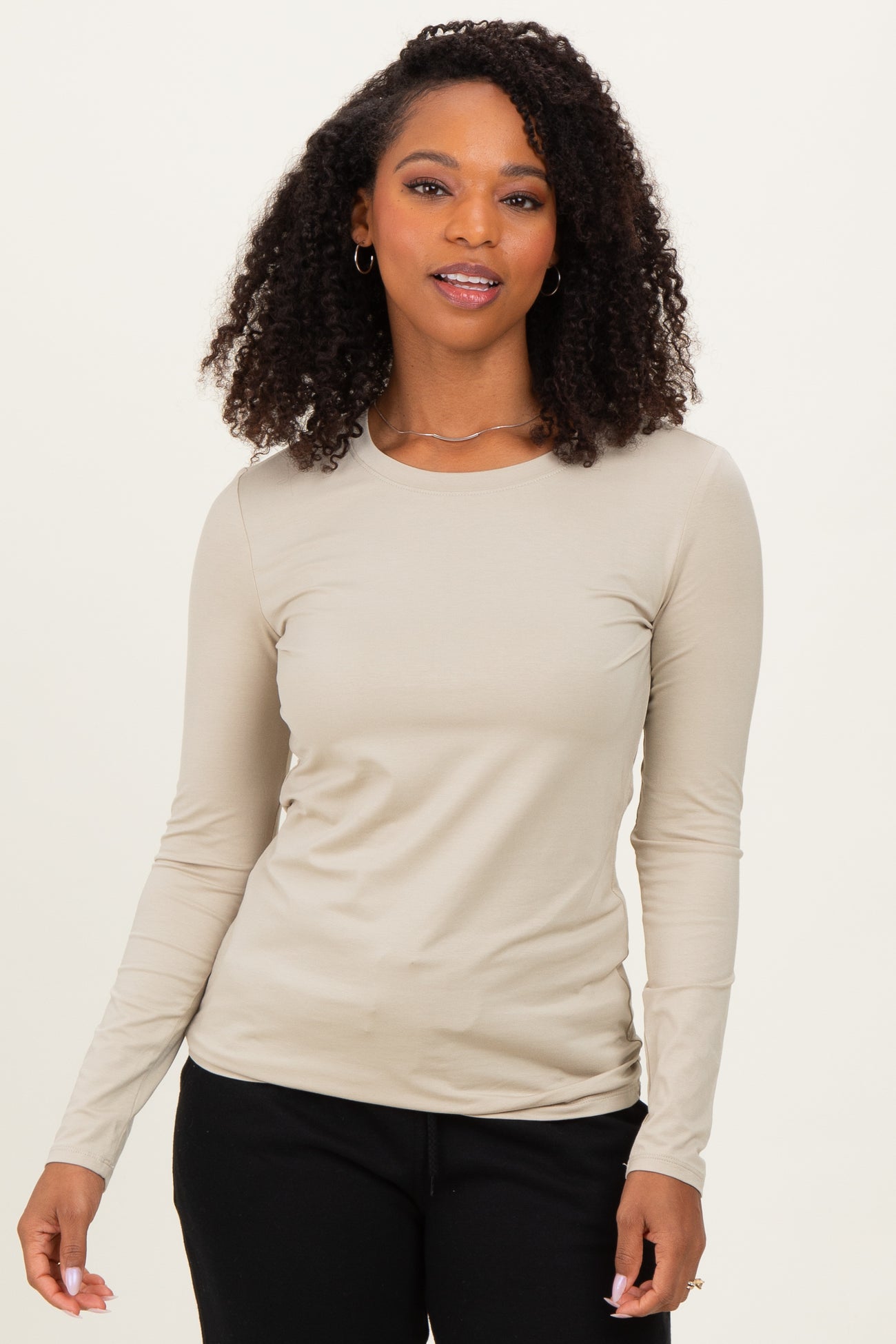 woman wearing a light beige long sleeve fitted top with a round neckline and subtle stretch