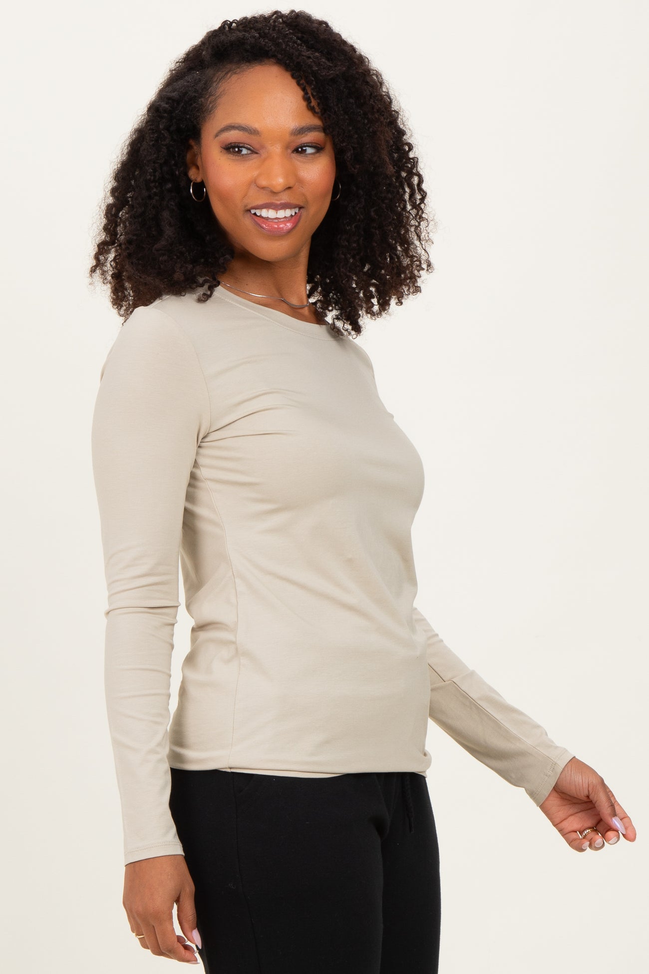 woman wearing a beige long sleeve fitted top with a round neckline and minimal seams