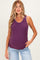 woman wearing a purple maternity tank top with contrasting stitching and light blue jeans, standing casually