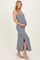 woman wearing a gray striped maternity maxi dress with a side slit and holding her baby bump