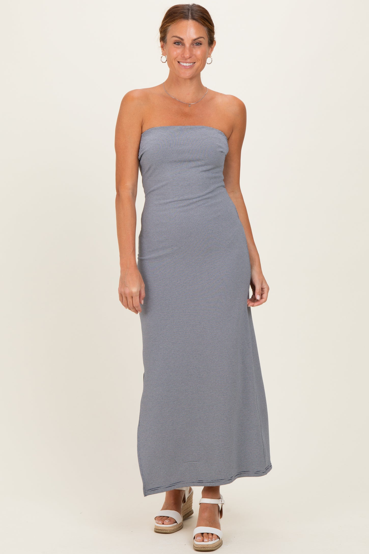 woman wearing a strapless gray striped maxi dress with a fitted bodice and relaxed skirt