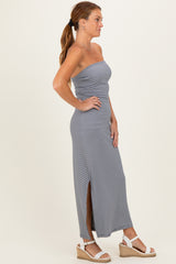 woman wearing a gray and white striped strapless maxi dress with a side slit and wedge sandals