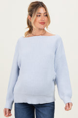 woman wearing a light blue oversized maternity sweater with a ribbed texture and off-the-shoulder neckline, showing her baby bump