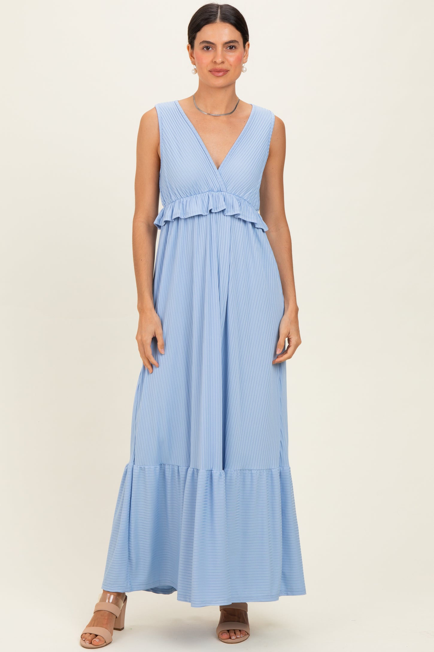 woman wearing a light blue sleeveless maxi dress with a ruffled bodice and tiered bottom